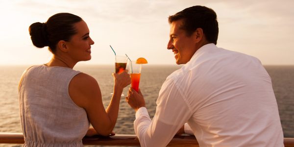 romantic young couple toasting with cocktail on cruise ship